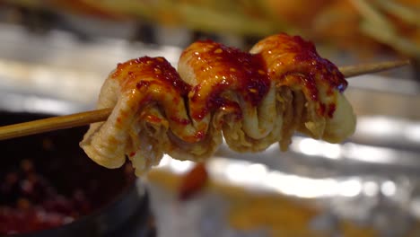 one oden on wooden stick covered with spicy korean sause in busan street market