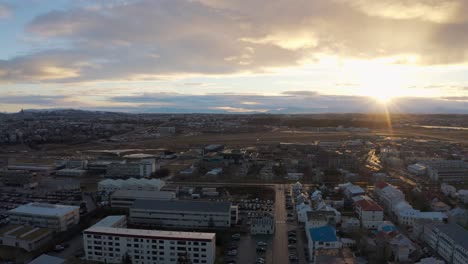 Incredible-aerial-view-of-Reykjavik-at-sunset,-capital-of-Iceland,-drone-flying-sideways