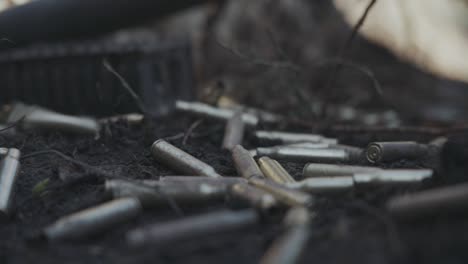 imágenes cinematográficas en cámara lenta de cartuchos de balas que caen en el suelo del bosque