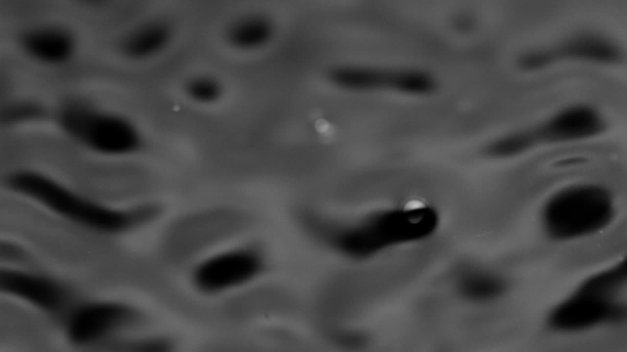 Splashes and drops on the surface of the liquid. Abstract Black Background Water vibration. 4K slow motion 100 fps, ProRes 422, 10 bit