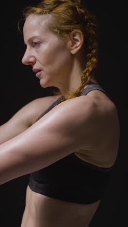 fotografía de estudio de video vertical de una mujer madura con ropa de gimnasia haciendo ejercicios de estiramiento