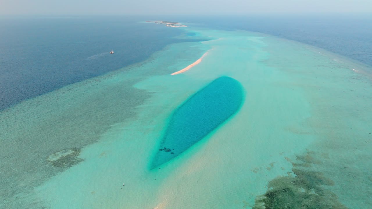 An awe-inspiring aerial drone view captures the Rasdhoo Sandbanks glowing under the soft, golden light of sunset in the Maldives.