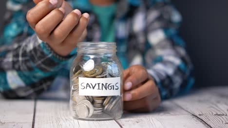 child boy hand hold a saving coins jar