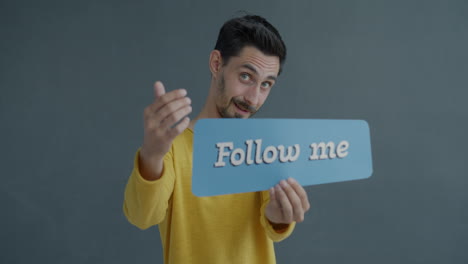 man holding a sign that says "follow me"