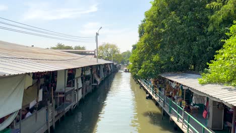 a serene boat ride through bangkok's khlong lat mayom floating market, showcasing vibrant stalls and lush greenery under bright daylight