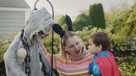 mom with a baby in her arms near the skeleton that decorated the house for halloween