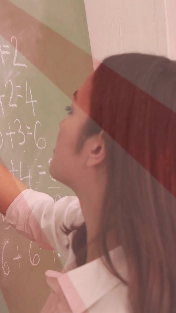 Vertical video: Teacher reaching up writing addition on chalkboard color overlay appearing in class