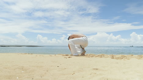 un tipo bailando capoeira en la playa.