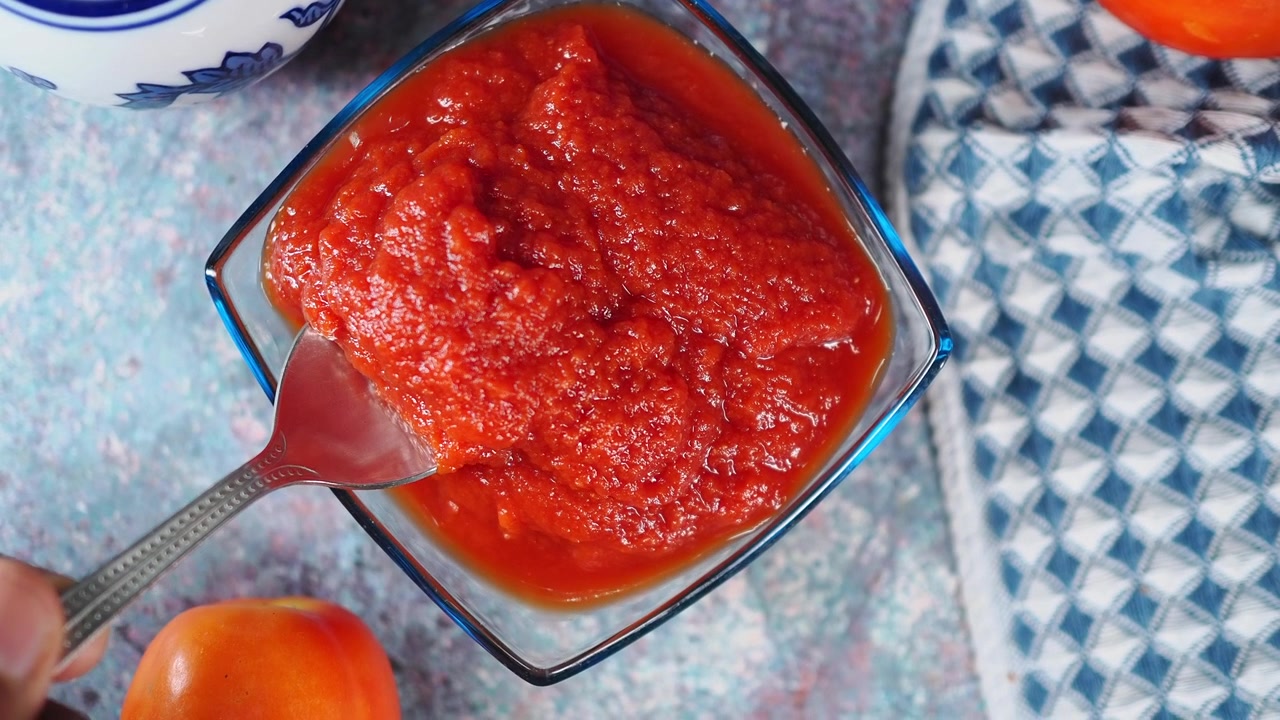 Cucchiaio che preleva salsa di pomodoro fresca da una ciotola di vetro