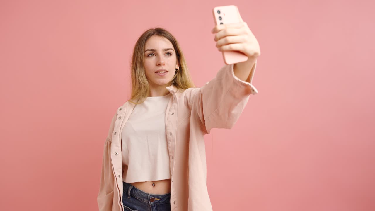 Giovane donna che si scatta selfie su sfondo rosa