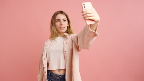young woman taking selfies on pink background