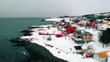 aerial view of houses and yards, black sand on the shore of the barents sea, dark, wet, winter day, in troms city, nordland, north norway - descending, drone shot