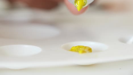 artist mixing yellow paint on palette