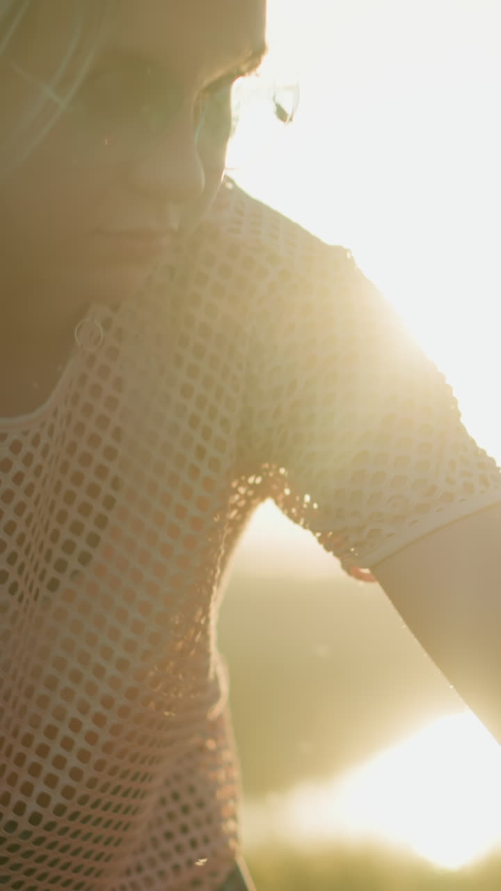 모터사이클을 청소하는 두 명의 여성의 클로즈업, 하나는 태양이 그녀의 뒤에 밝게 빛나는 작업에 초점을 맞추고, 다른 여성은 전면에 약간 흐릿합니다.