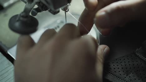 closeup of worker threading cotton on a sewing machine, clothing manufacturing factory