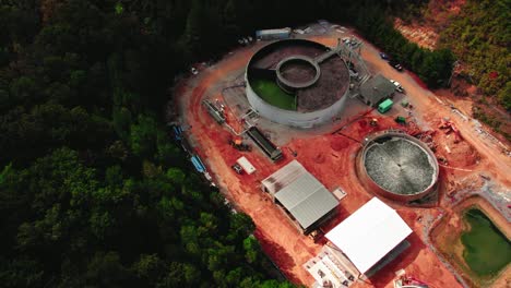 orbiting-aerial-of-wastewater-treatment-plant-in-construction-with-top-tank-lids-open