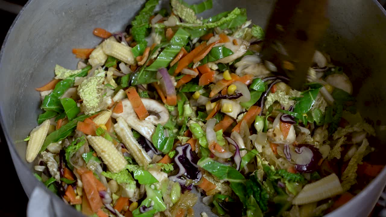 A cooking chef mixes vegetable stir-fry with a wooden spoon, embodying the essence of culinary preparation and food crafting