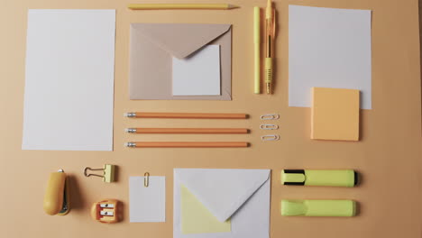 assorted stationery items are neatly arranged on a pale orange surface