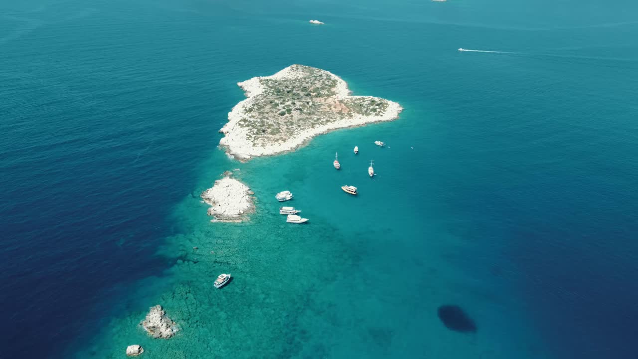 Aerial drone view showing heart shaped island surrounded by clear turquoise waters with anchored boats near Gocek in Fethiye Bay Mugla Province during bright calm summer conditions