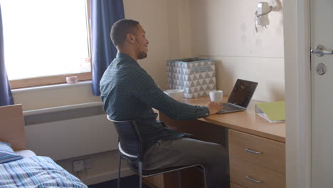 estudiante de sexo masculino trabajando en el dormitorio del alojamiento del campus