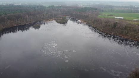 Vista-Aérea-Sobre-El-Lago-Cubierto-De-Hielo-En-El-Paisaje-Nevado-Del-Bosque-Invernal-En-Retie,-Bélgica