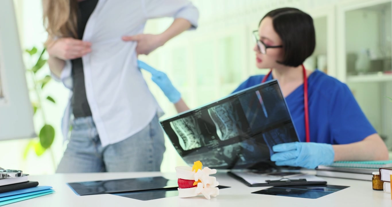 Vertebrae model against doctor studying woman spine xray images