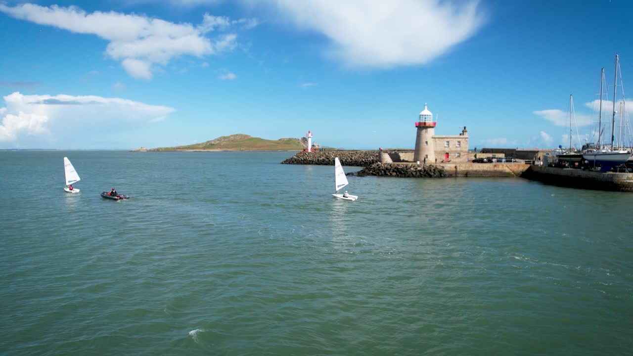 Boats leaving Howth Ireland sunny spring day blue water drone