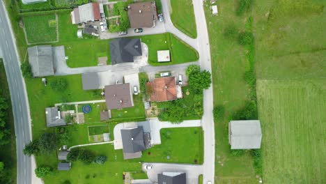 flying over small settlement of medium size family houses between green meadows