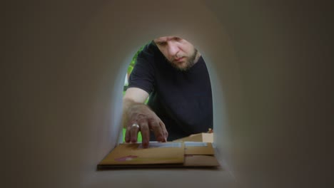 man picking up parcel and envelopes from front yard mailbox