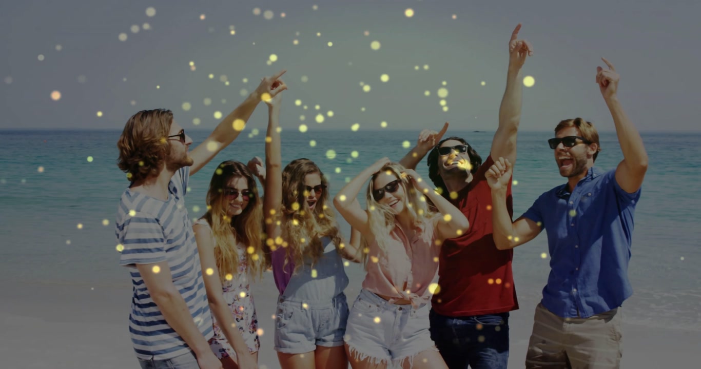 Six adults on beach, golden particles appearing, friends raising arms, celebrating shades marketing