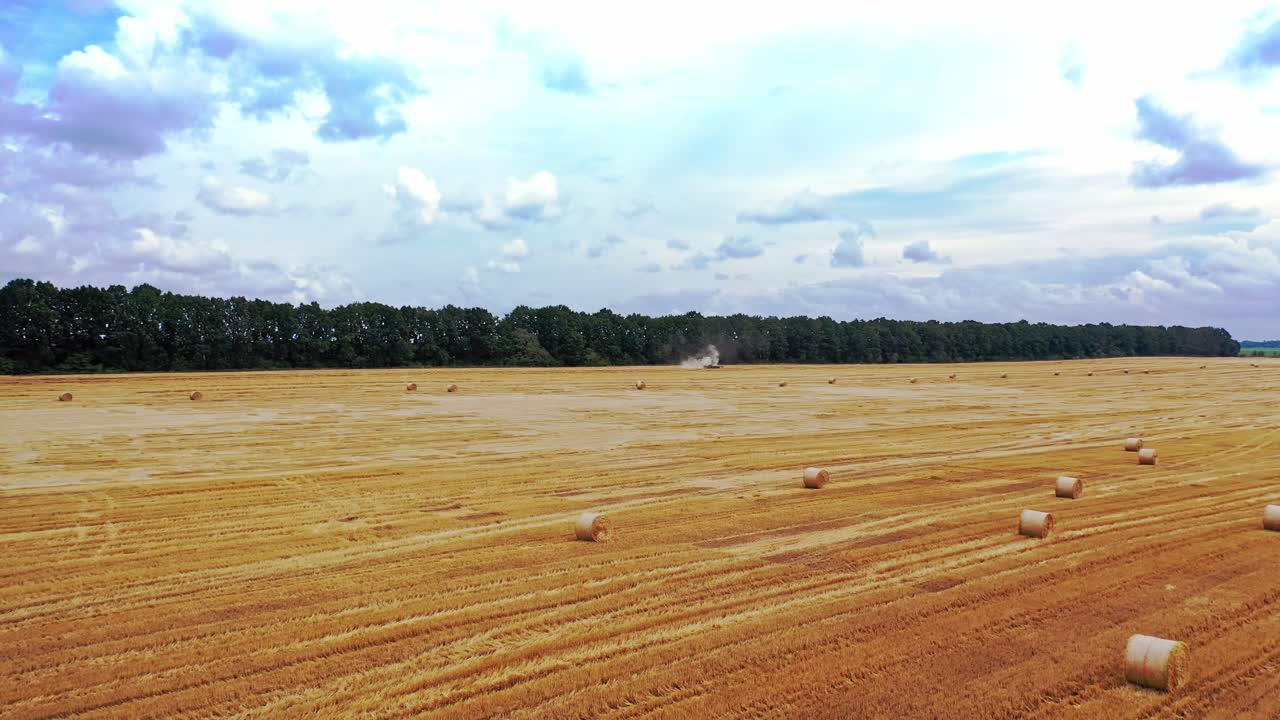 Aerial view on the golden field in a summer day. Round dried bales for livestock laying in the farmland. Motion camera top down.