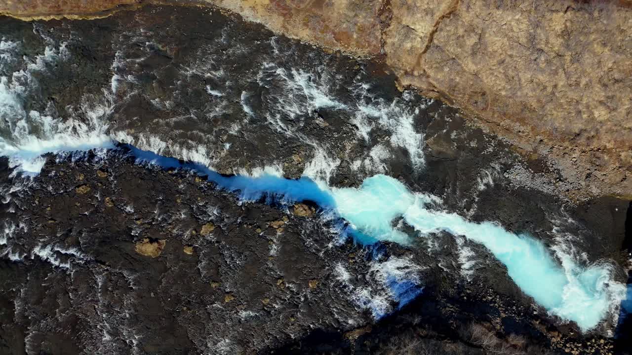 Vista aerea dall'alto della cascata di Brúarfoss in Islanda, con acque turchesi vivaci che scorrono attraverso un aspro territorio vulcanico in uno splendido paesaggio naturale