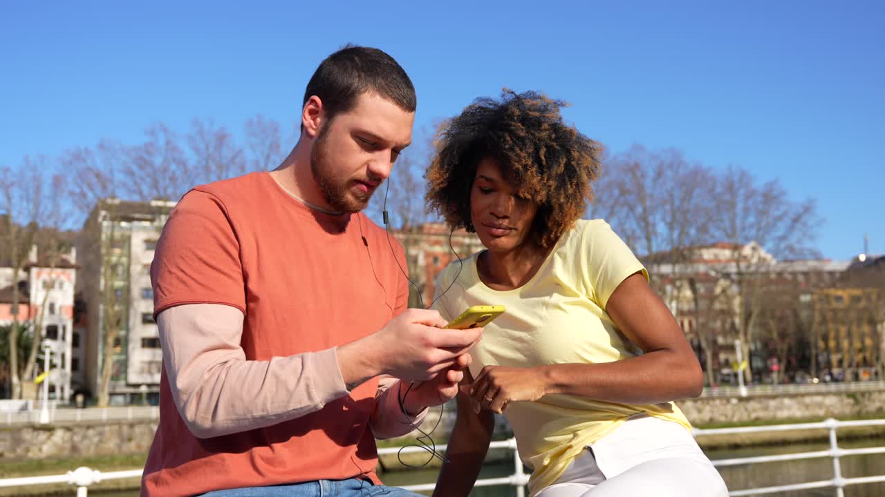 Couple listening to music on a phone outdoors