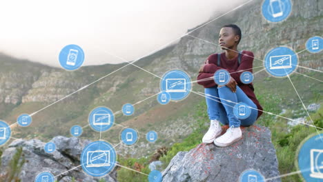 Animation-of-network-of-connected-icons-in-circles-over-african-american-woman-sitting-on-rock