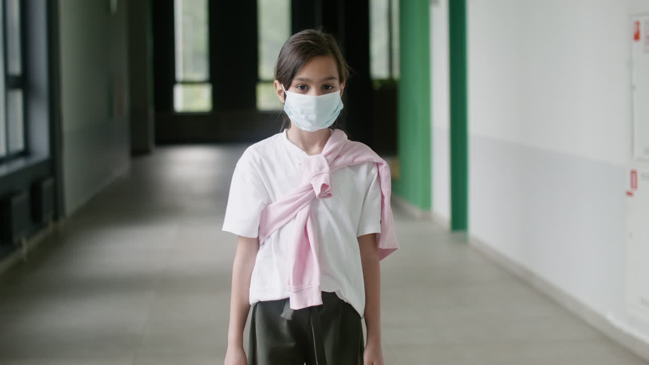 Schoolgirl with face mask in school corridor.