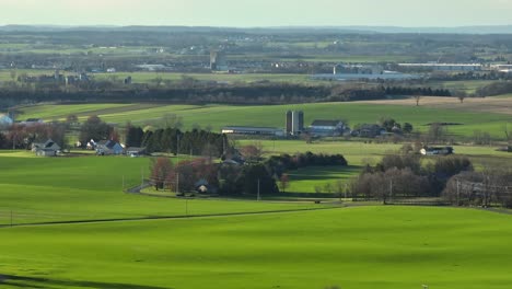 Aerial-zoom-shot-of-grass-and-agricultural-fields-at-sunset-time-in-rural-farmland