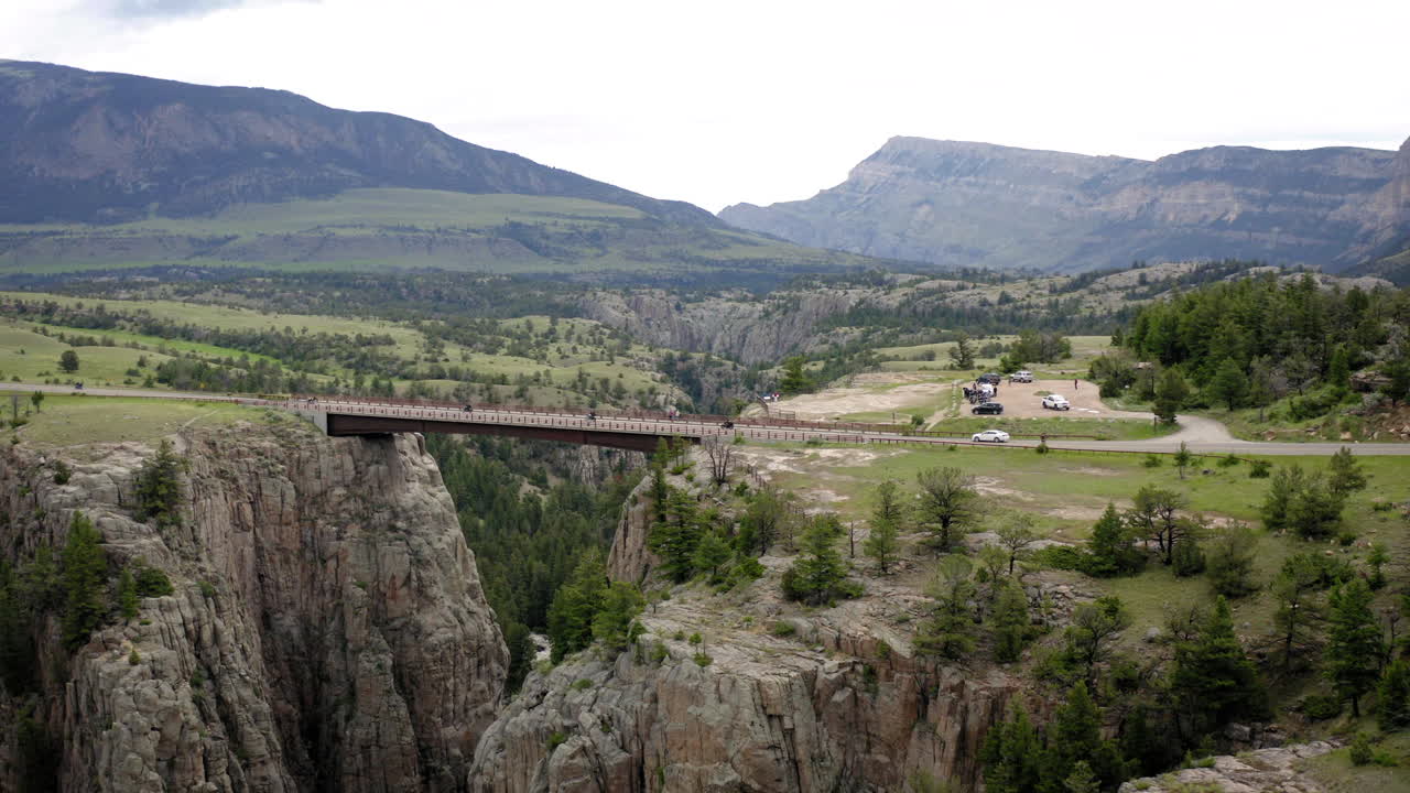A bridge spanning a deep canyon with majestic mountains in the background