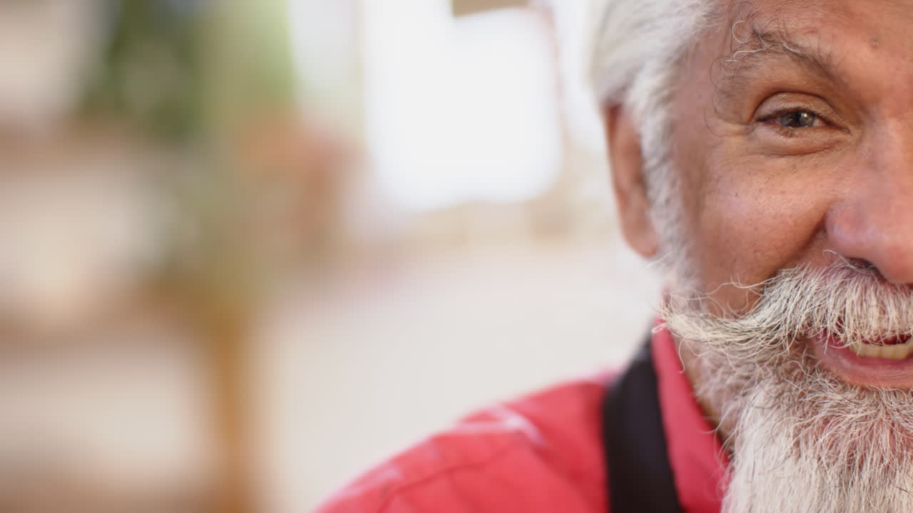 metà faccia di un felice vasaio biraciale con una lunga barba che sorride in uno studio di ceramica, in rallentatore