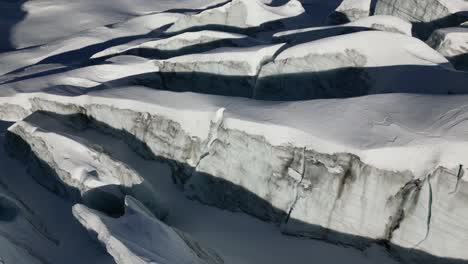 aerial,-tilt-down,-snow-covered-crevasses-in-the-swiss-alps,-mountains-in-winter