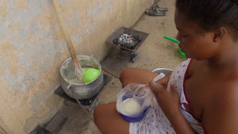 woman preparing banku, a ball of dough made with leavened flour, served with side dishes and stew, a typical ghanaian dish