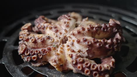 toma de seguimiento cinematográfica de un pulpo que se cocina sobre una barbacoa a la parrilla, capturando los detalles de la textura de las ventosas en los tentáculos del pulpo