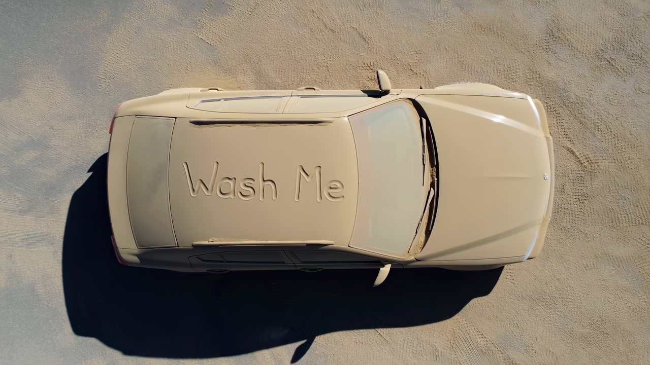 Aerial Dusty Car With Wash Me Message On Roof, Sunbaked Sand Ground, Long Shadow, Topdown Composition