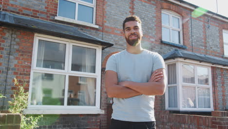 portrait of young man standing outside new home in urban street