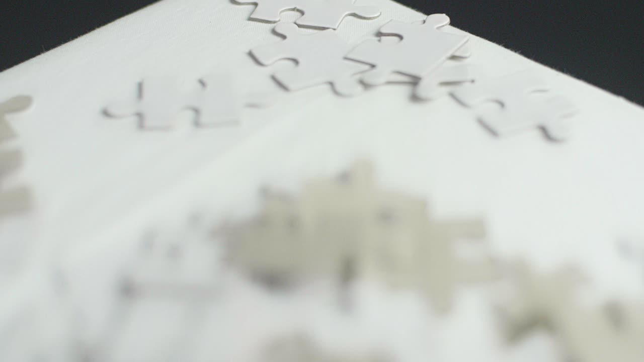 어두운 배경이 있는 흰색 표면에 무작위로 놓인 흰색 및 회색 퍼즐 조각