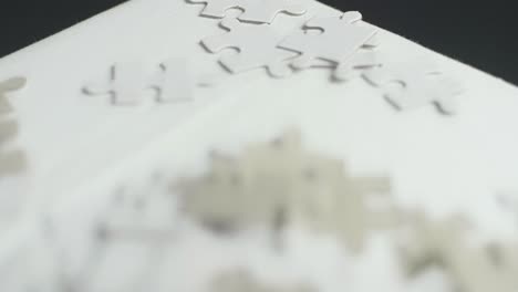 piezas de rompecabezas blancas y grises colocadas al azar sobre una superficie blanca con un fondo oscuro