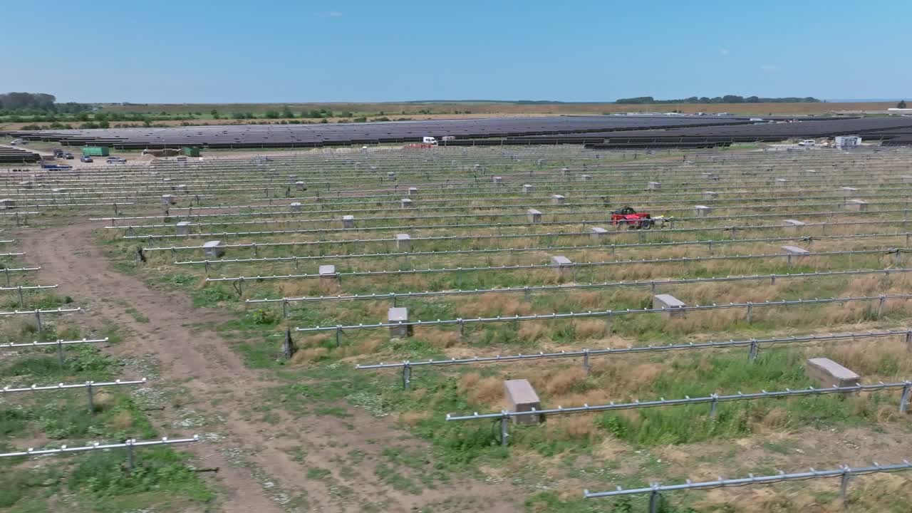 Drone view of a vast solar farm with green fields, sunny day