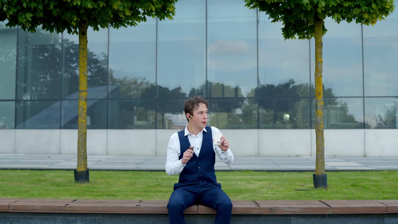 Young businessman enjoying a chocolate snack break outside a modern office