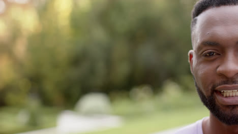 Portrait-of-happy-african-american-man-smiling-in-garden,-copy-space,-in-slow-motion