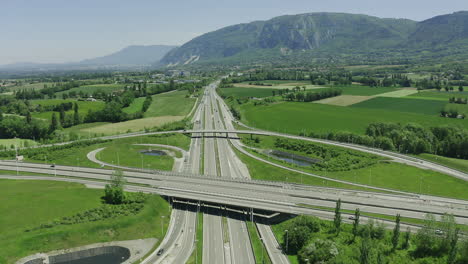 drone aerial of truck driving through motorway with green forest lake and mountains alps in the background summer 6