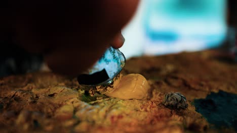 artist painter putting a pinch of yellow paint in his palette